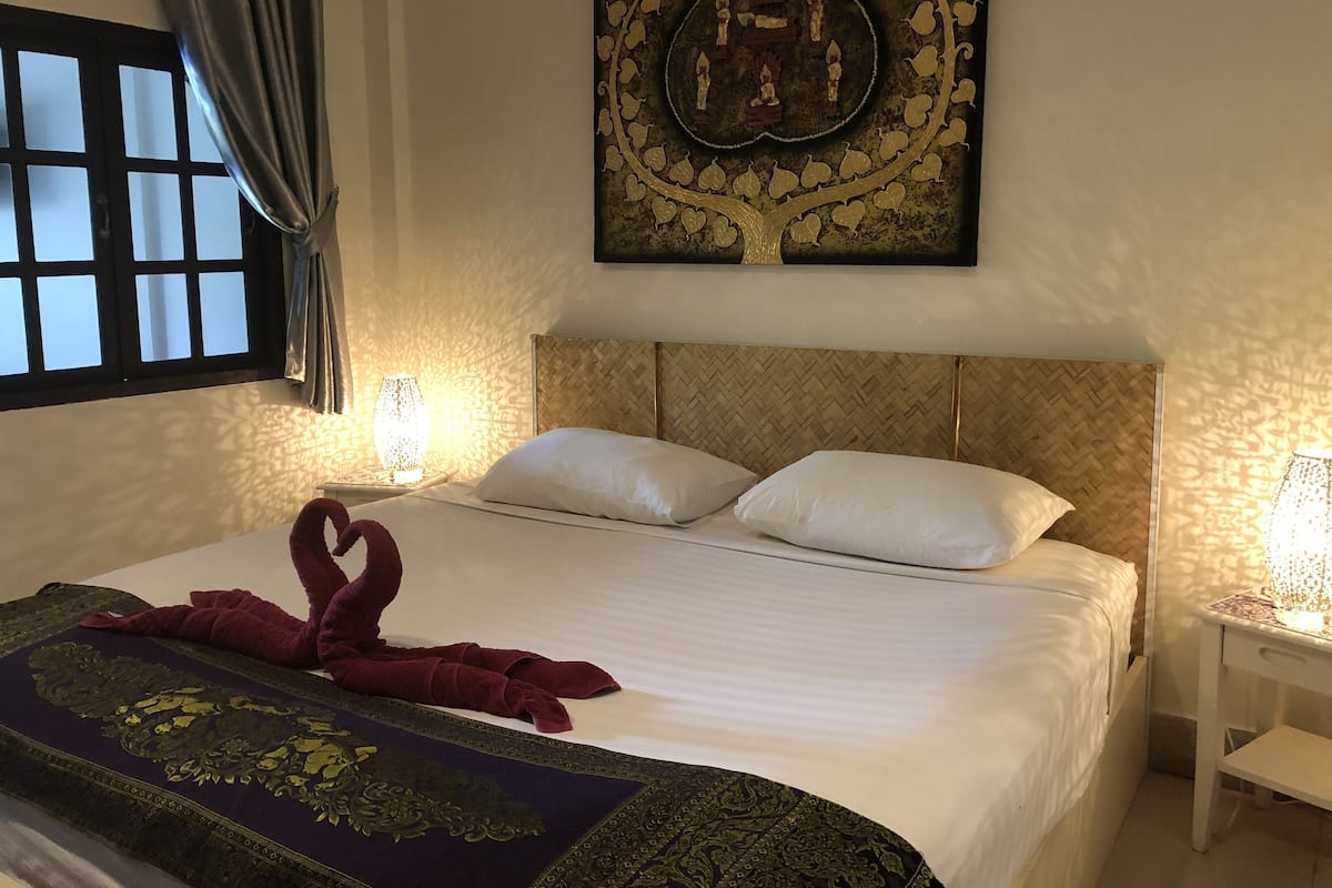 Una habitación de hotel con una cama grande, un tapiz decorativo y una ventana con cortinas.