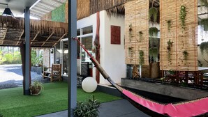 A modern outdoor seating area with a hammock, artificial grass, and bamboo decor. - Samui Zenity Hotel (Koh Samui)