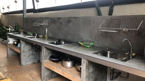 A kitchen with a marble countertop, stainless steel sink, and hanging plants. - Samui Zenity Hotel (Koh Samui)