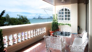 Un balcon avec une table et des chaises, une plante en pot, et une vue sur les bâtiments d’une ville et un pont.