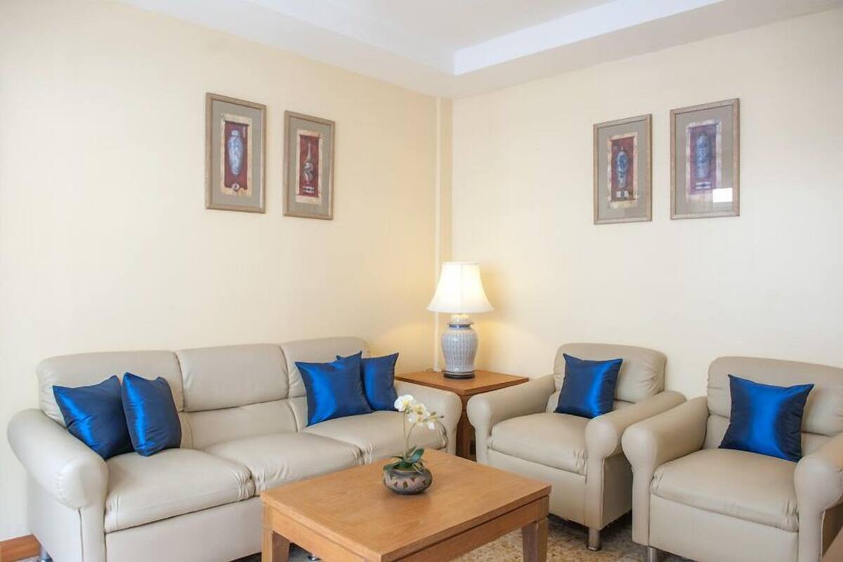 Un salon avec un canapé beige, des coussins bleus, une table basse en bois et une lampe.