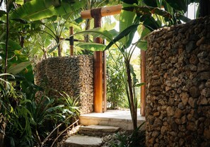A stone pathway leading to a wooden structure with a bamboo pole.