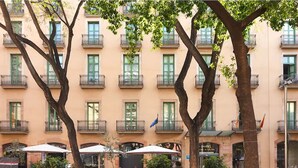 Fachada de hotel con varios balcones, mobiliario exterior y plantas en macetas.
