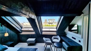 Un interior moderno con tragaluces, un sofá, una silla y un televisor en la pared.