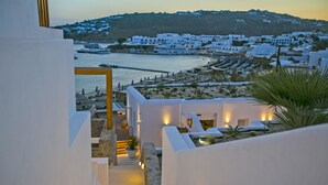 Un hotel frente al mar con edificios blancos, vistas al océano y una colina al fondo.