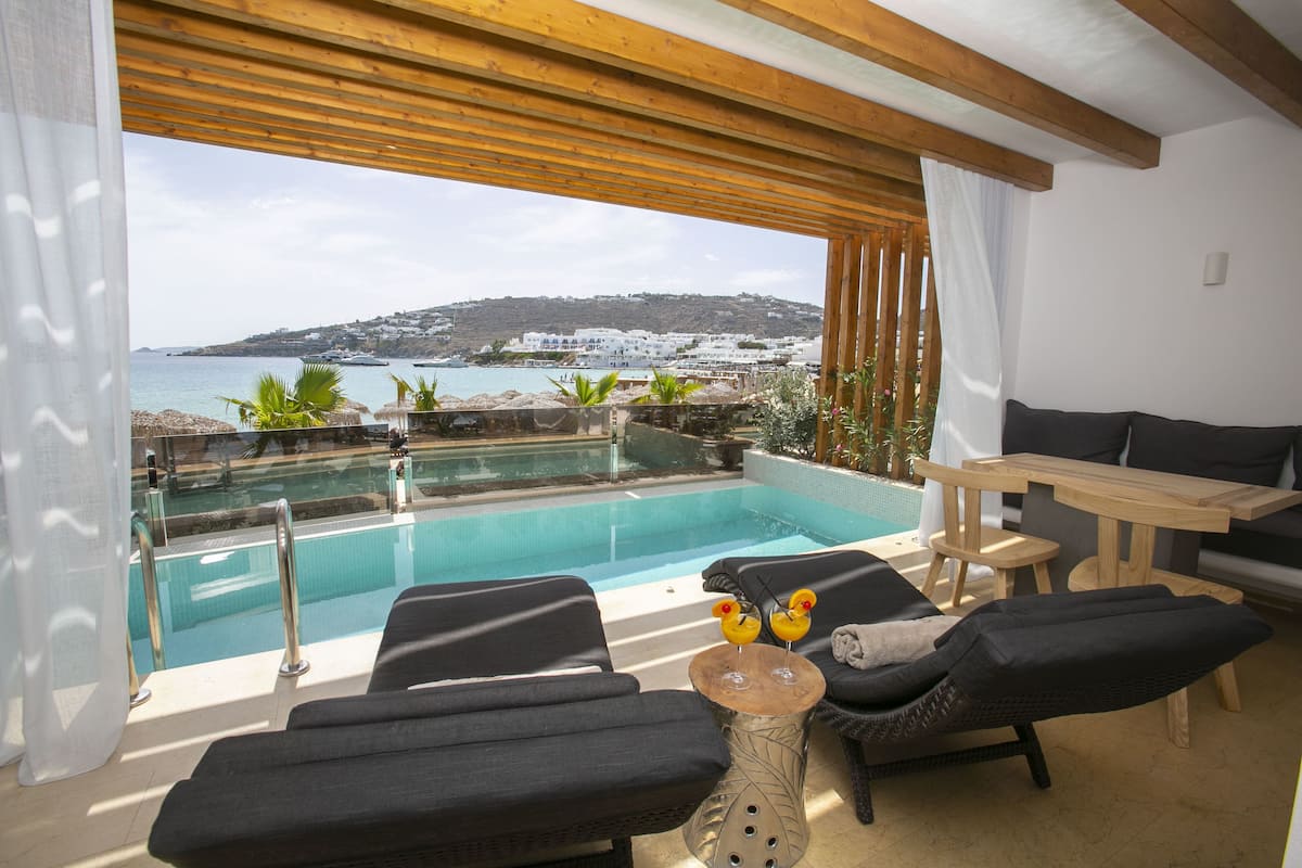 Ein moderner Außenbereich mit Lounge-Möbeln, einem Pool, Liegestühlen und einem Holztisch.