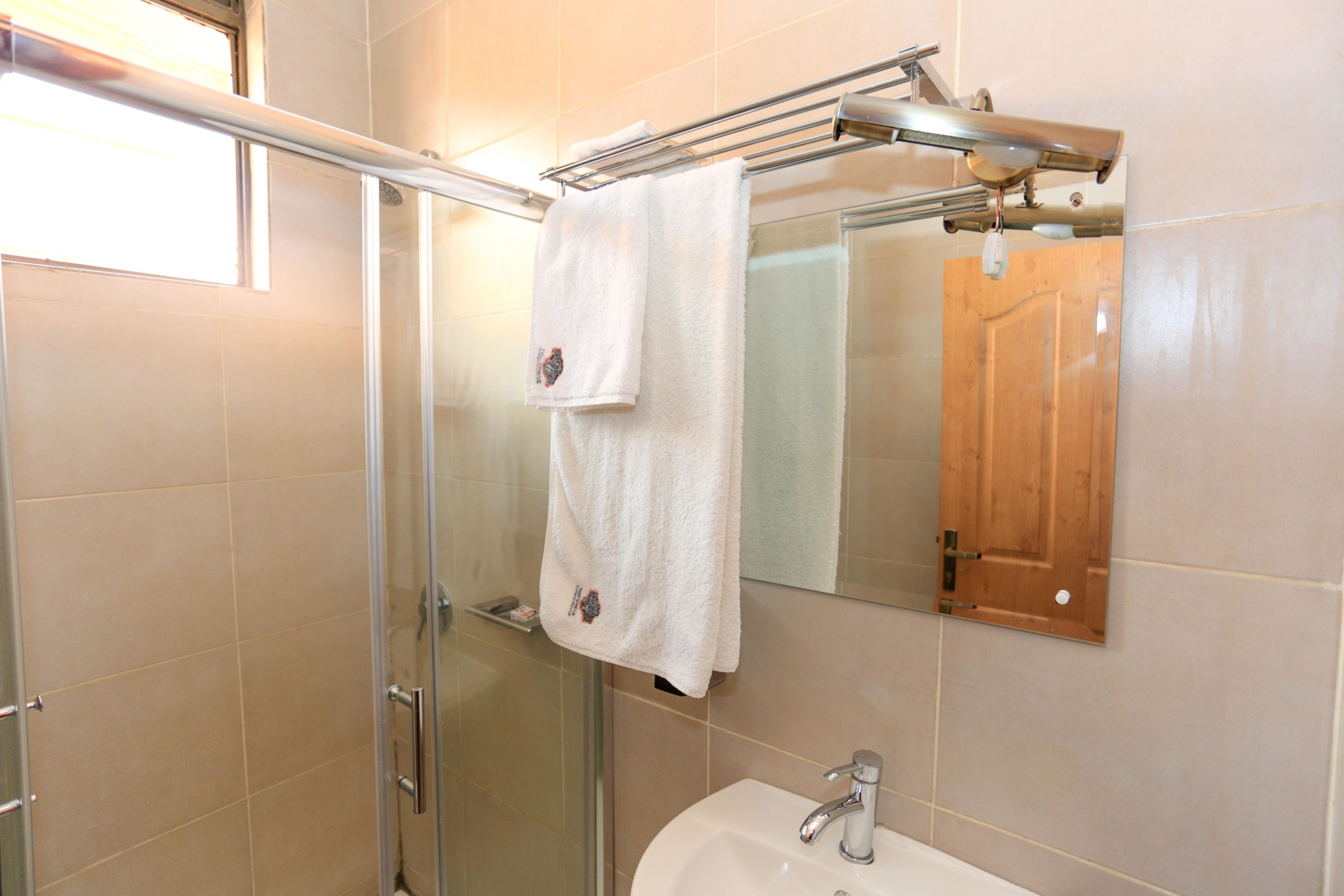 Een badkamer met een glazen douchecabine, een witte wastafel met een chromen kraan en een handdoek aan een rek.