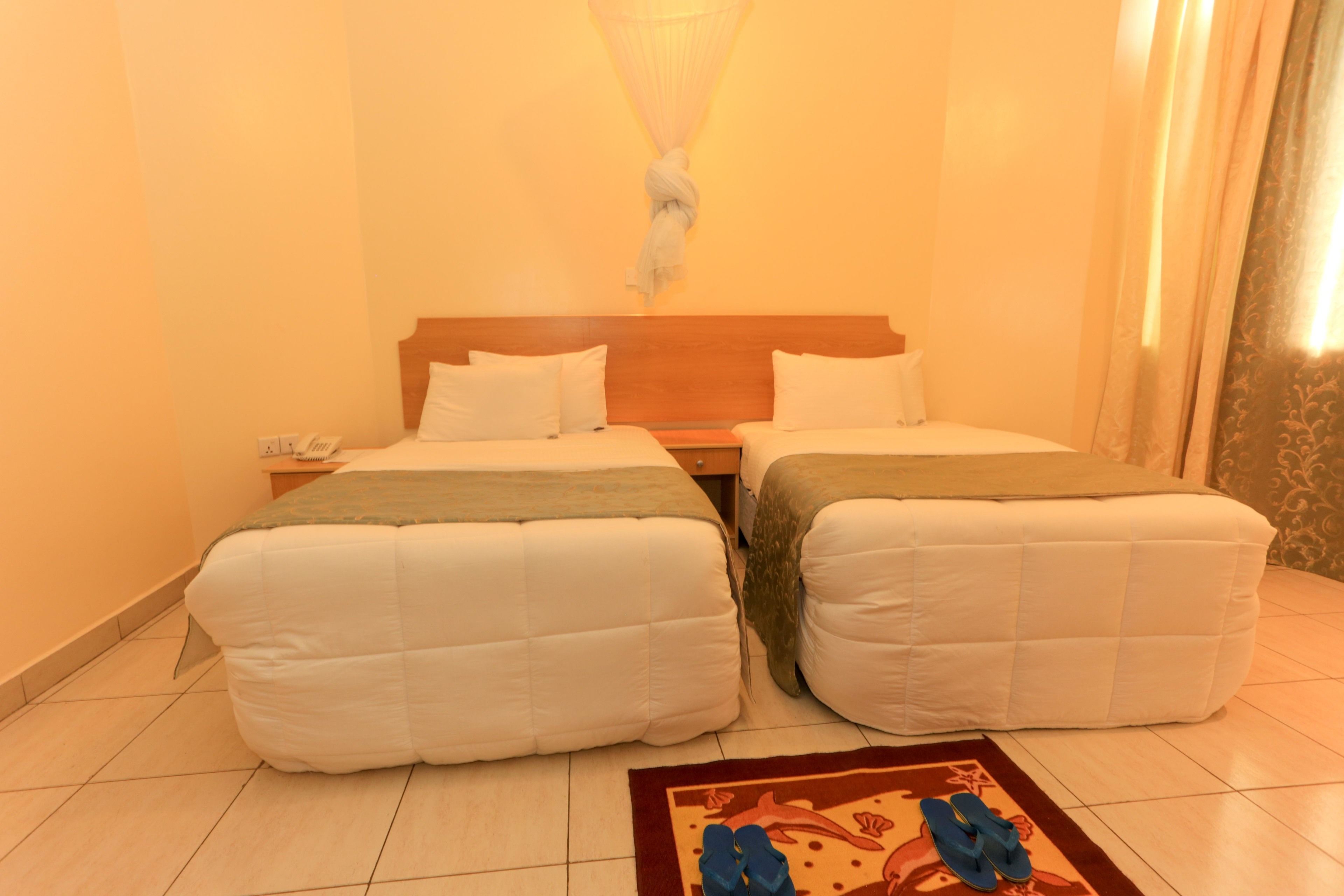 A hotel room with two beds, a bedside table, a telephone, and a decorative rug.