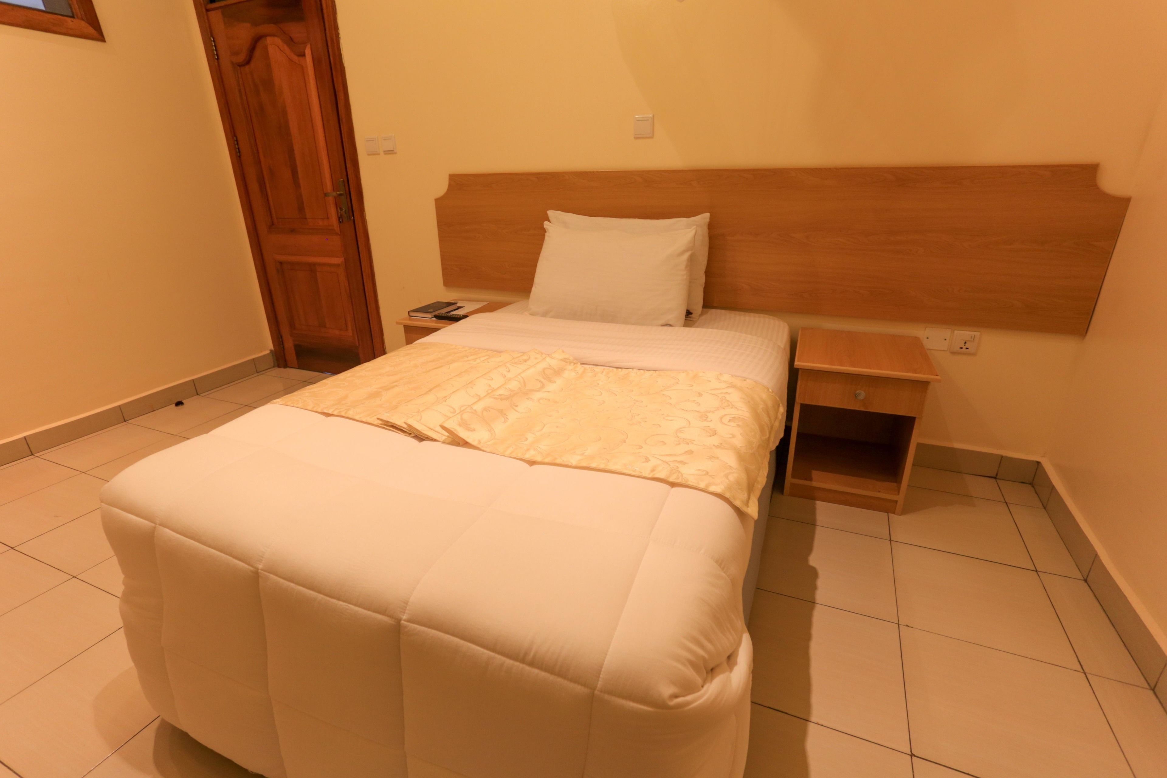 A neatly arranged bedroom with a bed, bedside tables, and a wooden headboard.