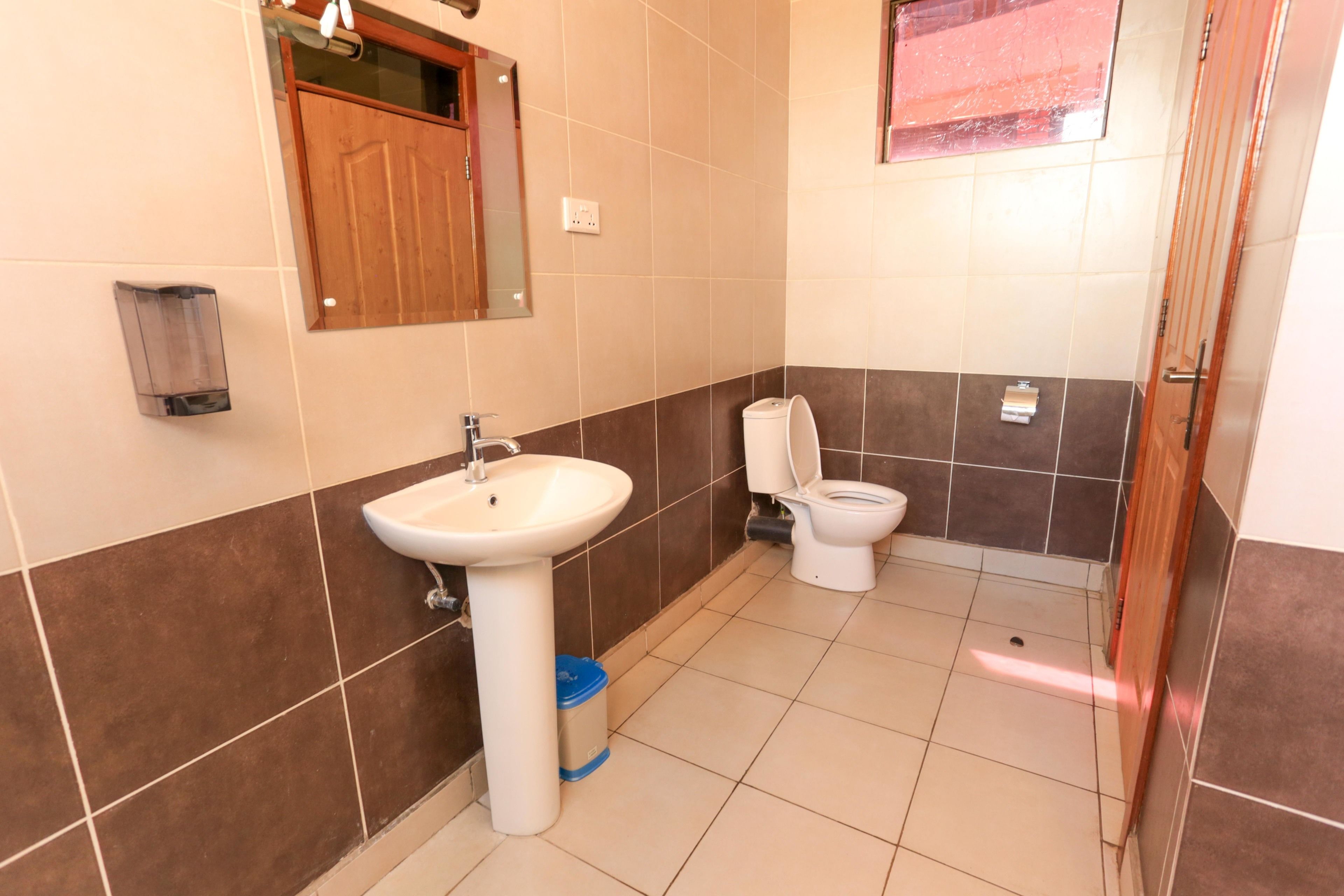 Un baño con lavamanos, inodoro y espejo.
