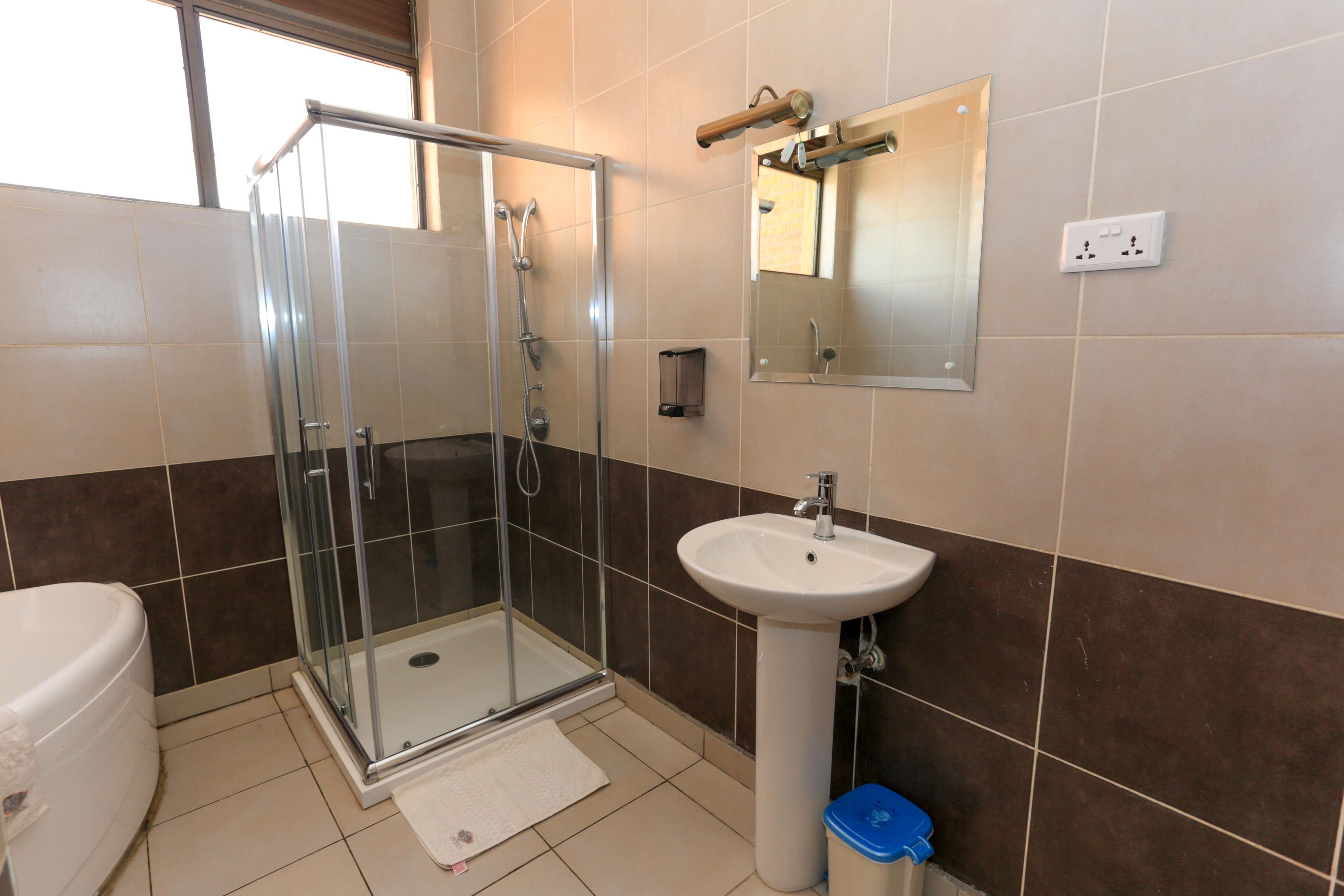A bathroom with a glass-enclosed shower, a white sink, and a toilet.
