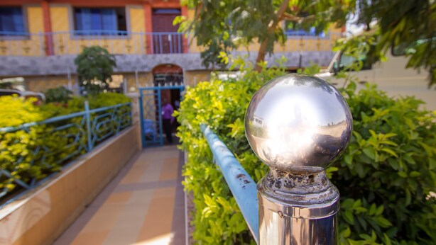 A metal railing with a spherical finial, a pathway, and a building with a balcony in the background. - Grande Hotel (Isiolo)