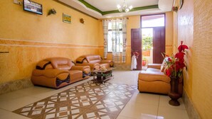 A hotel lobby with a sofa set, a coffee table, and a vase with flowers. - Grande Hotel (Isiolo)