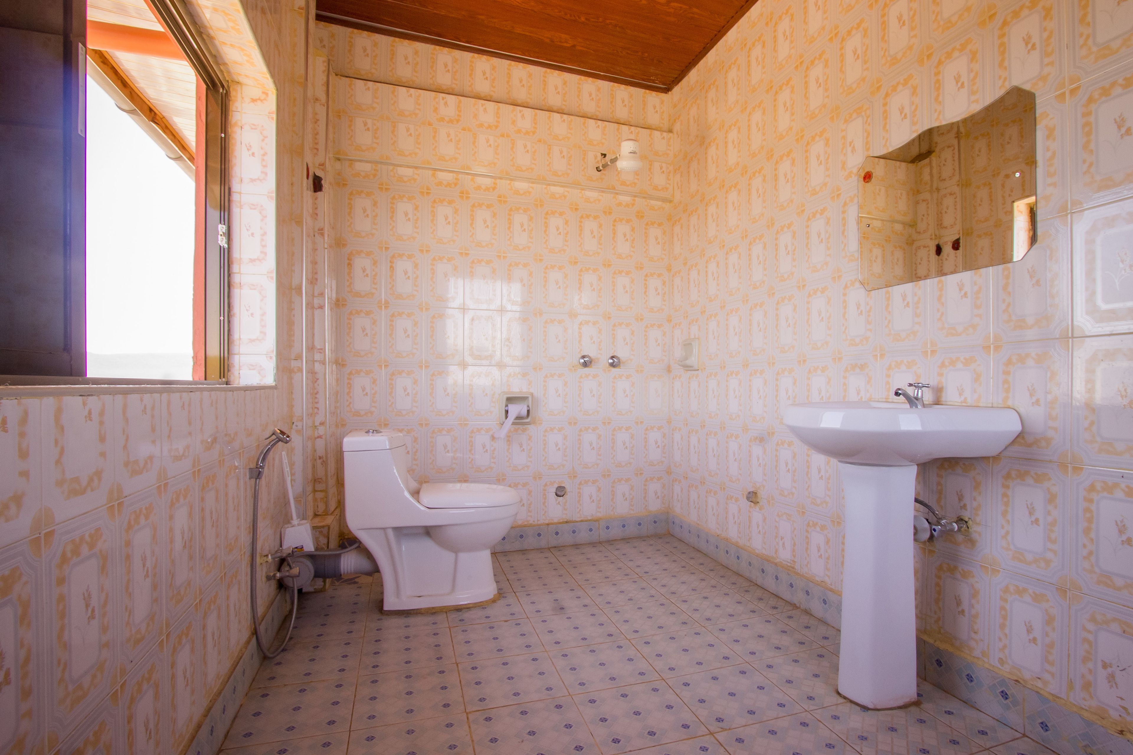 A bathroom with patterned walls, a toilet, a sink, and a mirror.