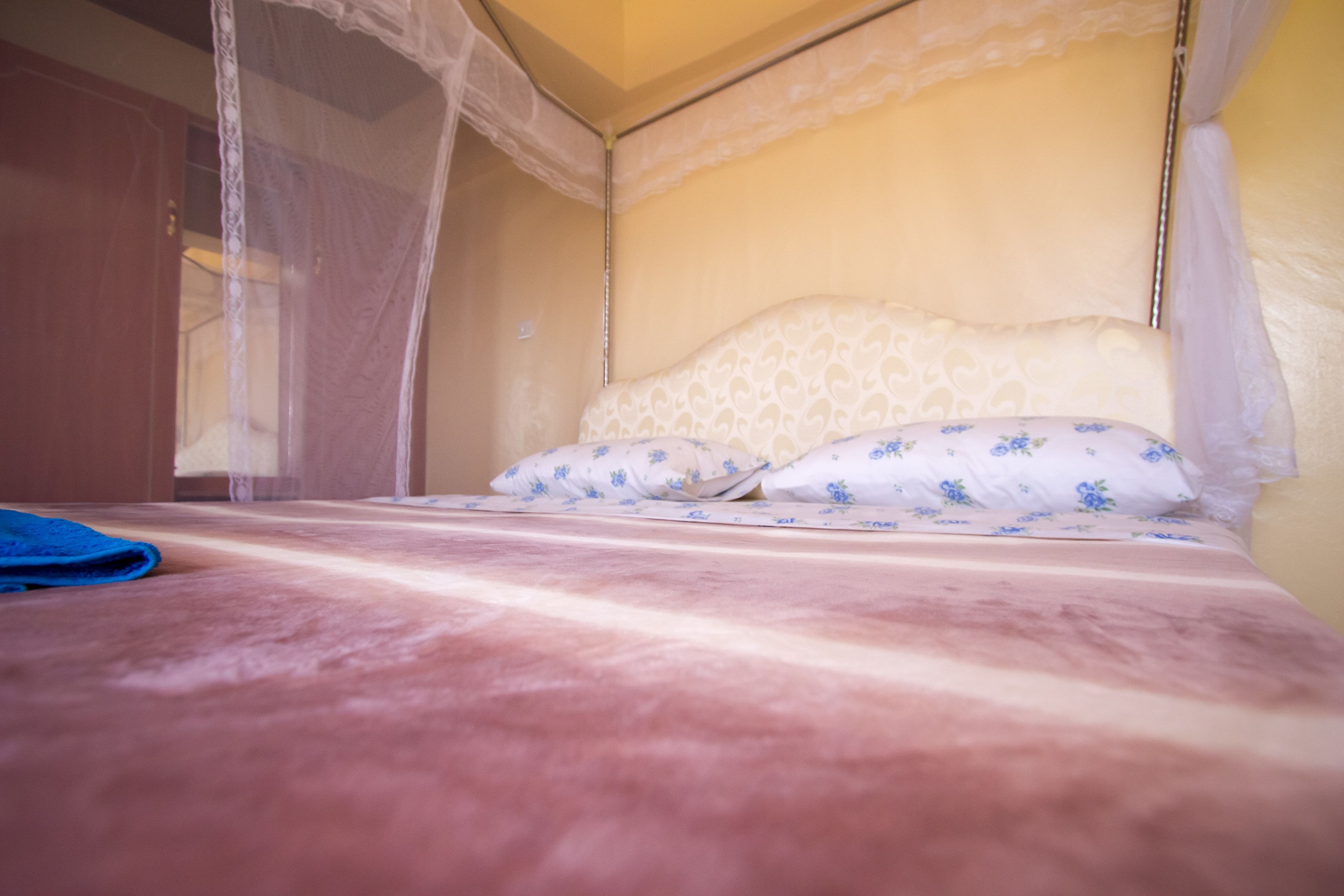 Un lit à baldaquin, une literie à motifs floraux et une serviette bleue sur le sol.
