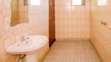 Un baño con papel tapiz estampado, un lavamanos, un espejo y techo de madera.