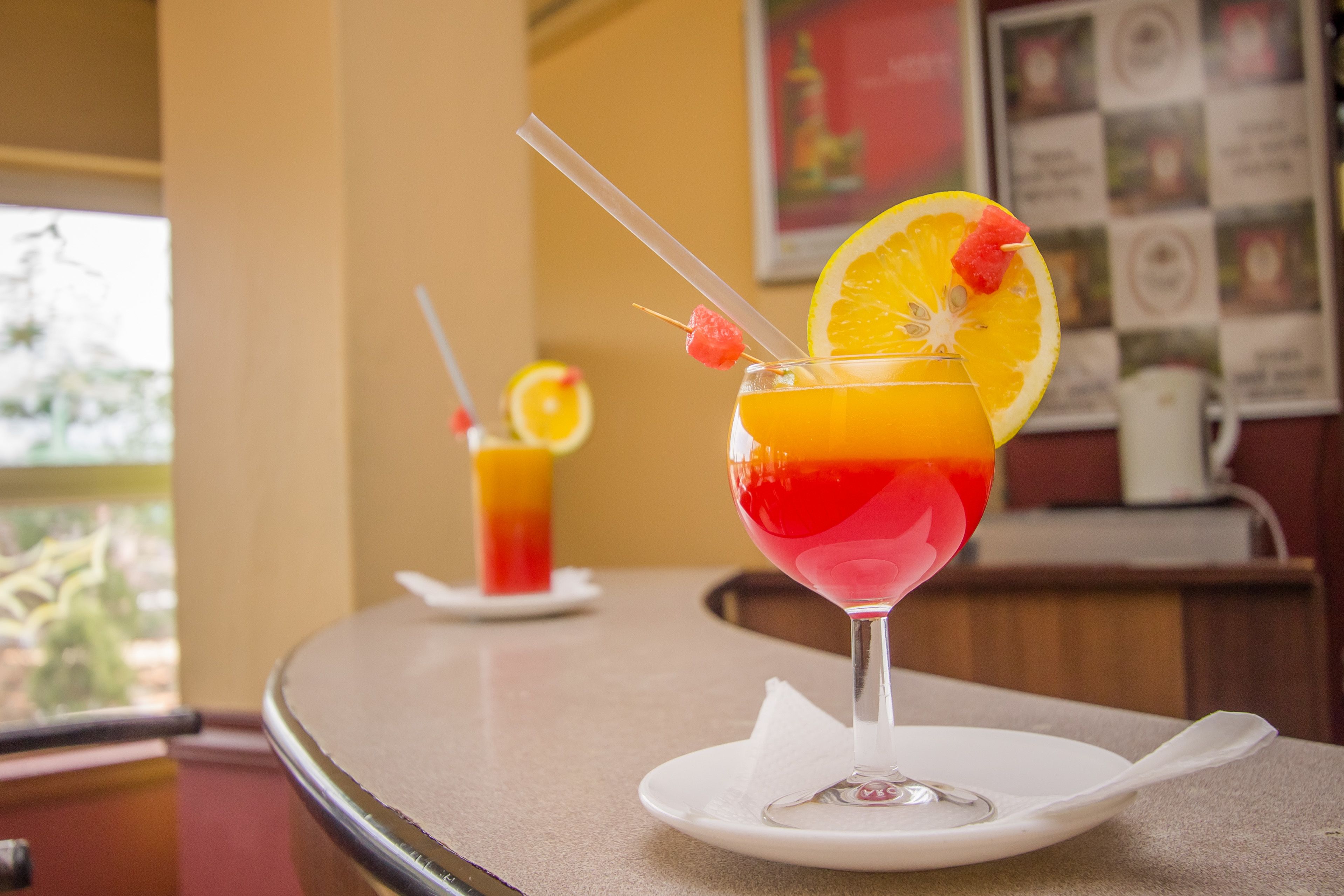 Two cocktails on a table with a menu board in the background.