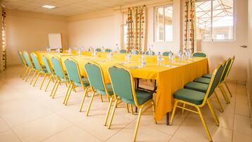 A conference room with multiple tables and chairs, a whiteboard, and windows with curtains.