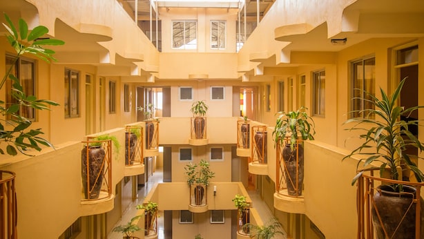 Ein mehrgeschossiges Atrium mit Balkonen, üppigen Kübelpflanzen und einem offenen Innenhof.