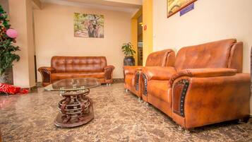 A lobby with two leather sofas, a glass coffee table, a potted plant, and a Christmas tree.