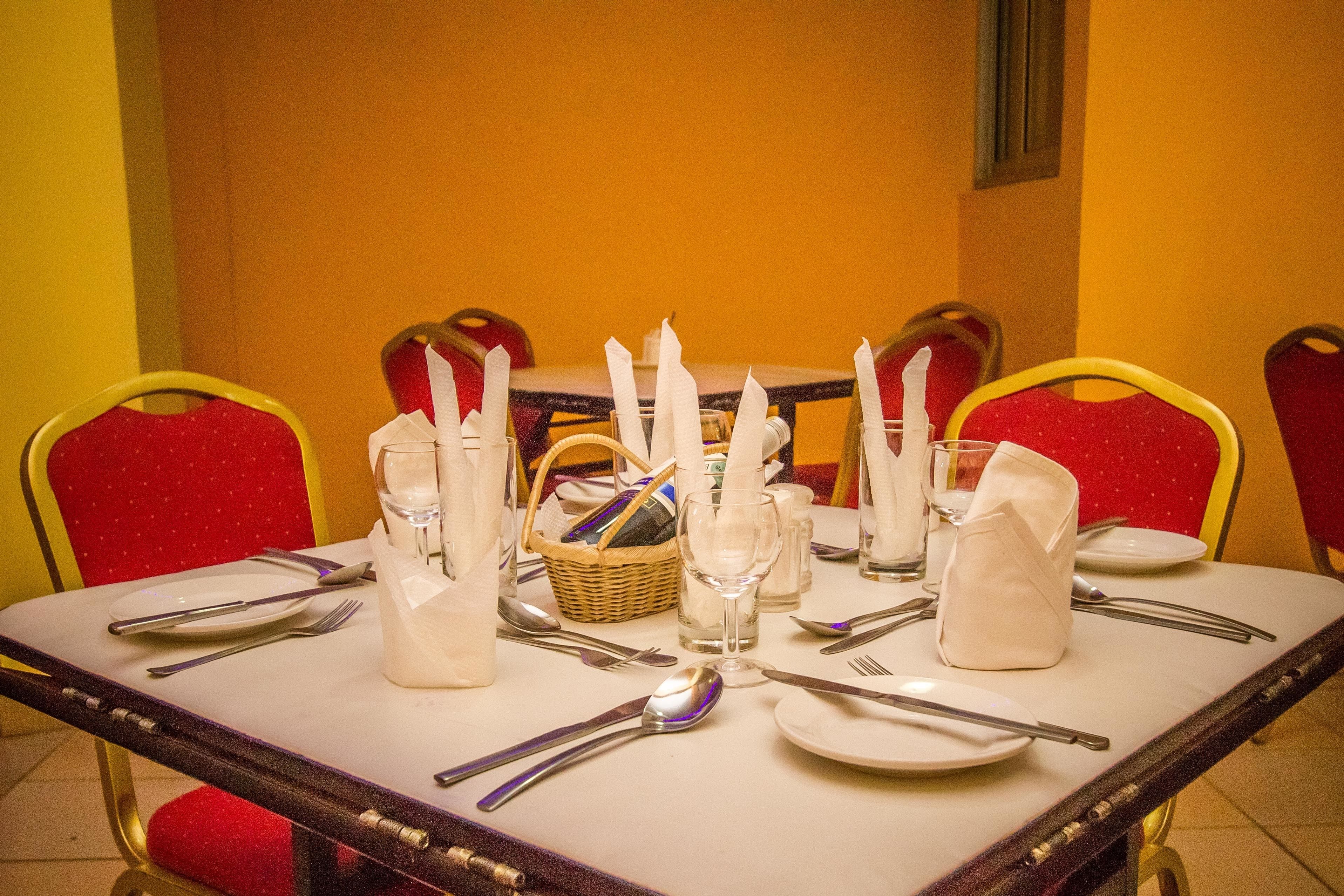 Una mesa de comedor preparada con mantel blanco, cubiertos y velas.
