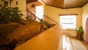 Una habitación con una escalera de madera, una gran formación rocosa y vistas a una puerta que da al exterior.