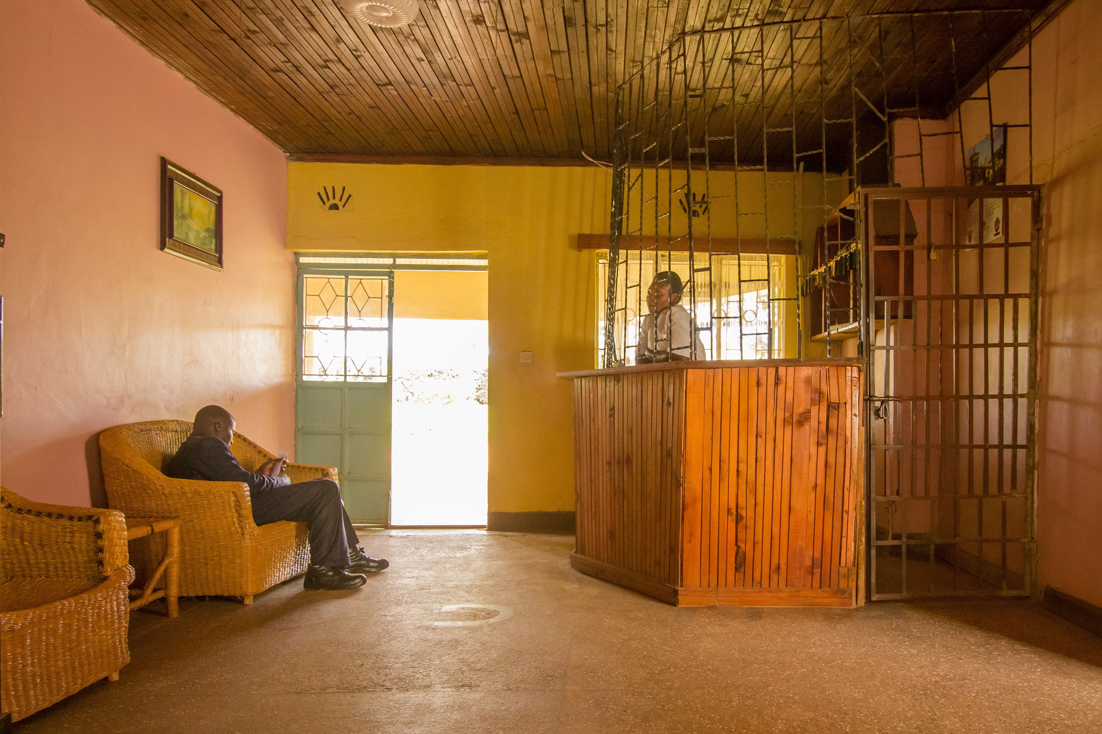 A reception area with a wooden counter, wicker furniture, and a door leading outside.