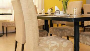 Comedor con pared amarilla, una mesa redonda y sillas tapizadas con un estampado.