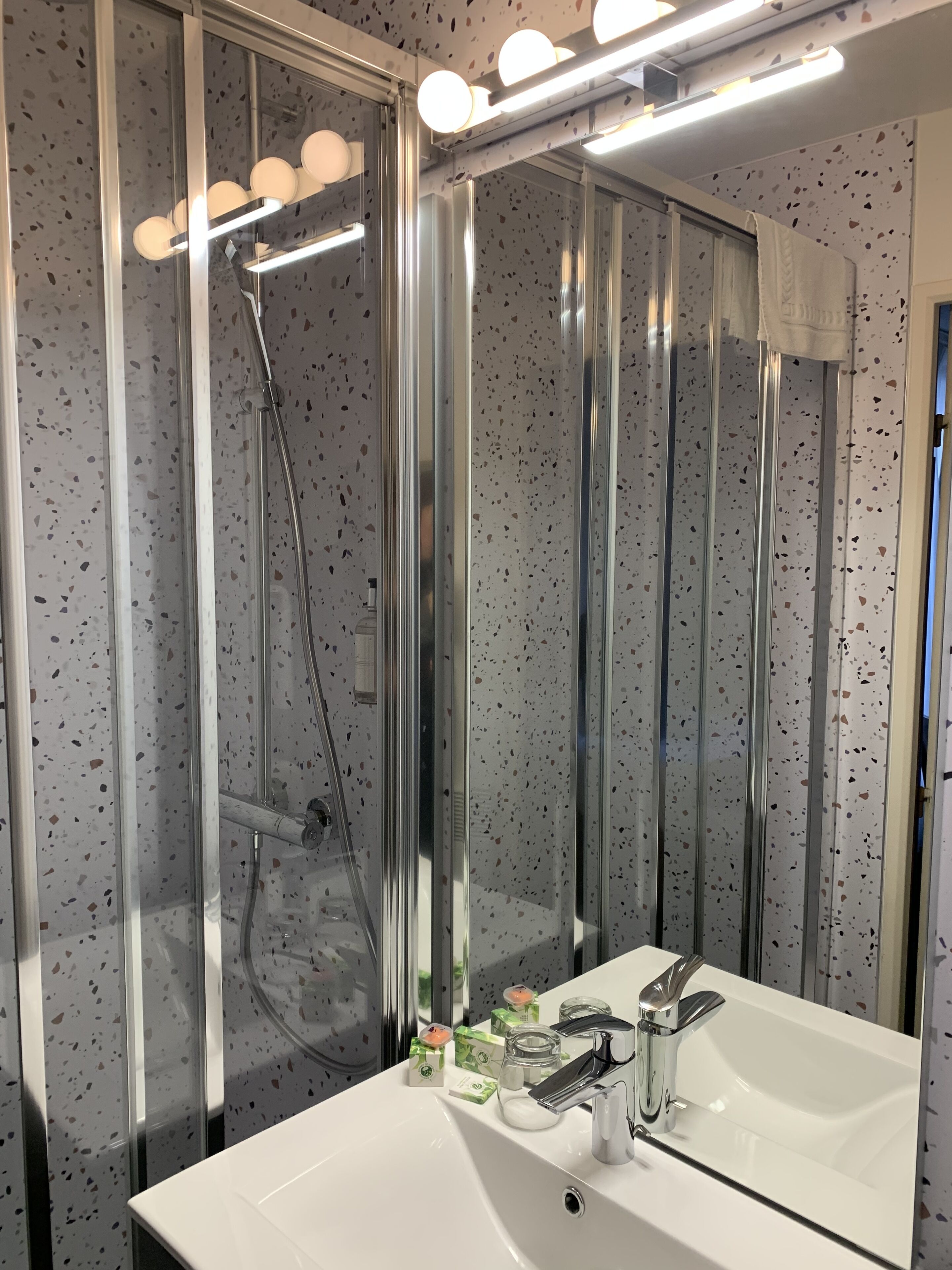 A modern bathroom with a glass-enclosed shower, a white sink with a mirror, and a ceiling light fixture.