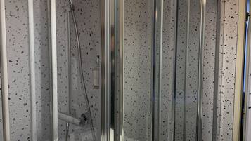 A modern bathroom with a glass-enclosed shower, a white sink with a mirror, and a ceiling light fixture.