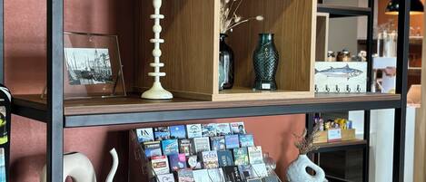 A shelf with various items including a bottle, decorative vases, and postcards.
