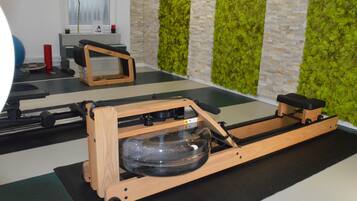 A rowing machine in a room with a green wall and a window.