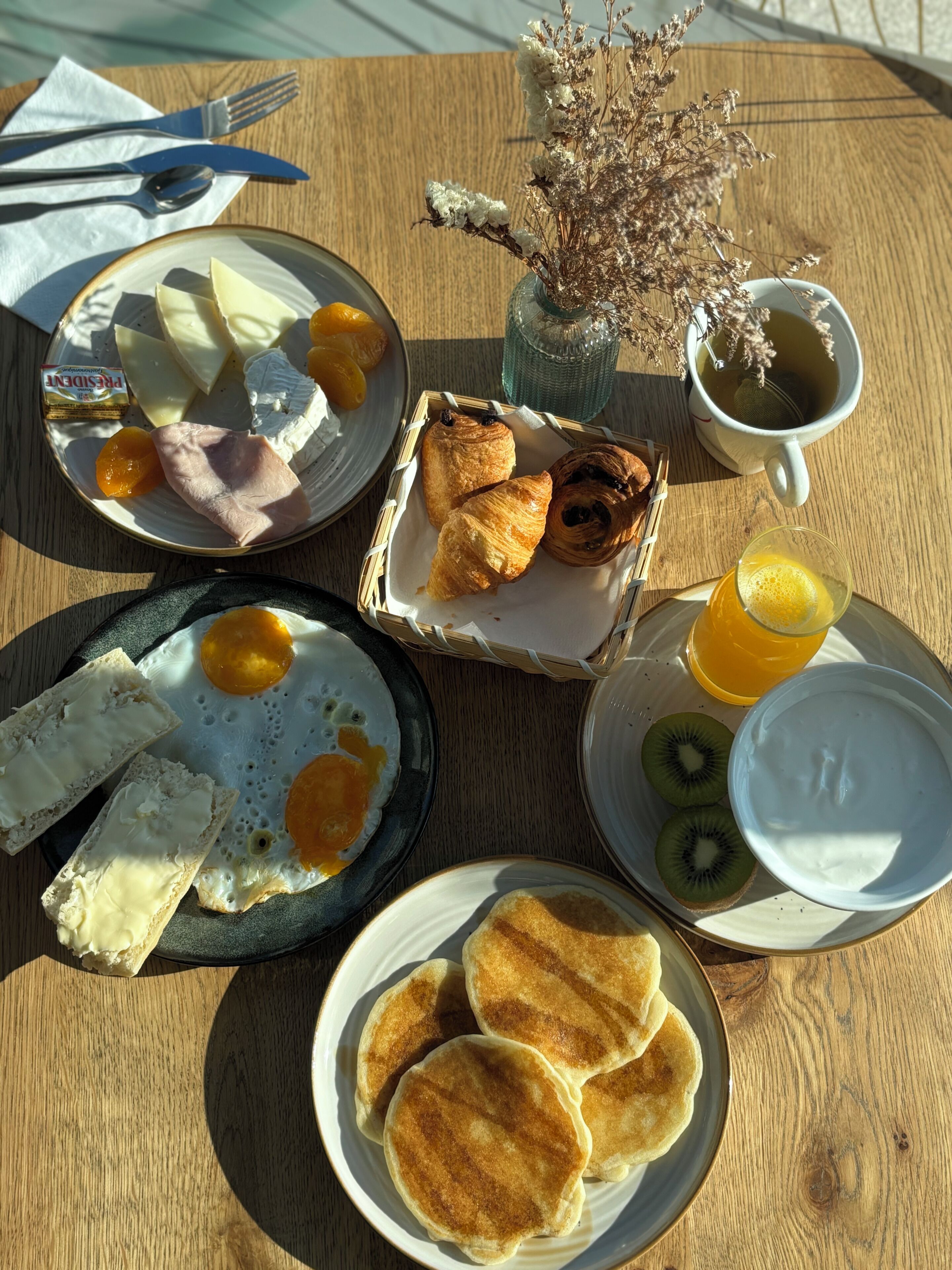 Una mesa de desayuno con diversos alimentos, incluyendo huevos, tostadas, pasteles y una taza de té.