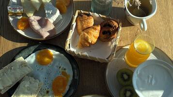 Una mesa de desayuno con diversos alimentos, incluyendo huevos, tostadas, pasteles y una taza de té.