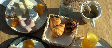 Uma mesa de café da manhã com diversos alimentos, incluindo ovos, torradas, doces e uma xícara de chá.