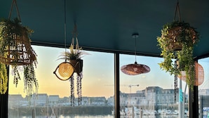 A modern cafe with large windows offering a view of a harbor and cityscape. - Hôtel Ambassadeur (Cherbourg-en-Cotentin)