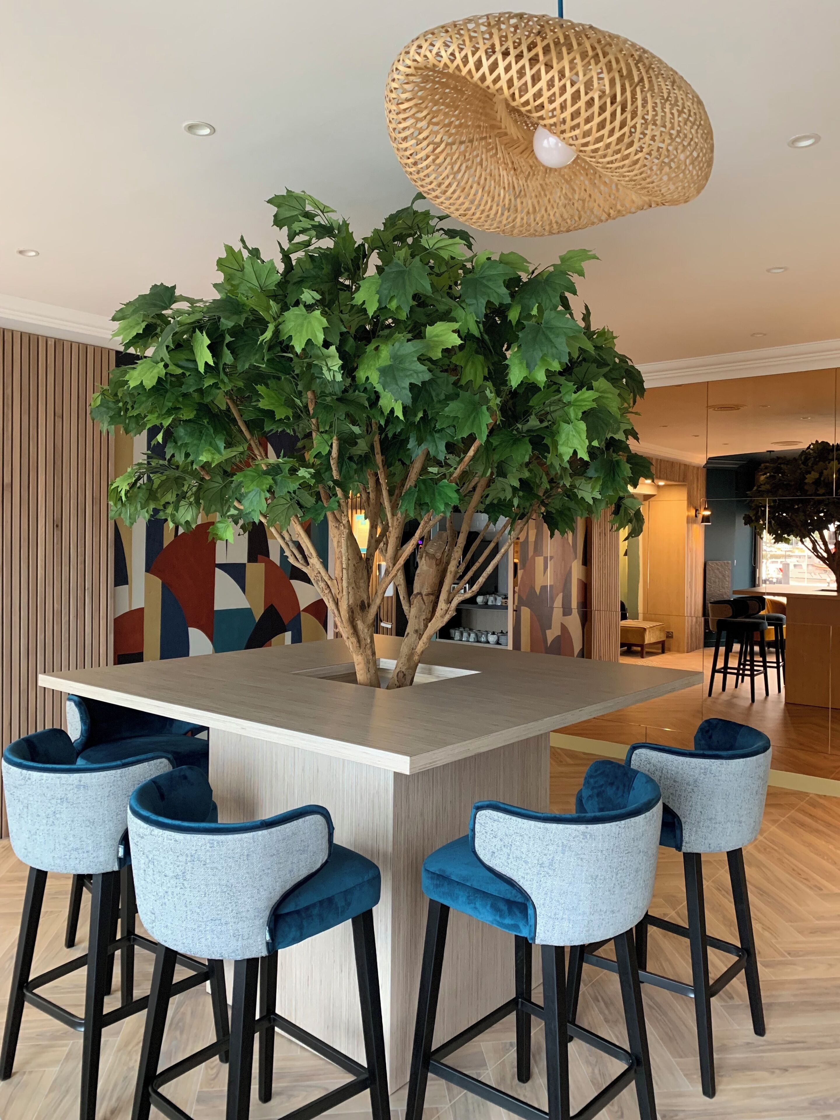 Uma área de bar moderna com uma ilha central, banquetas e uma luminária pendente.