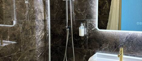 Un baño moderno con bañera, ducha, tocador con lavamanos y espejo con iluminación.