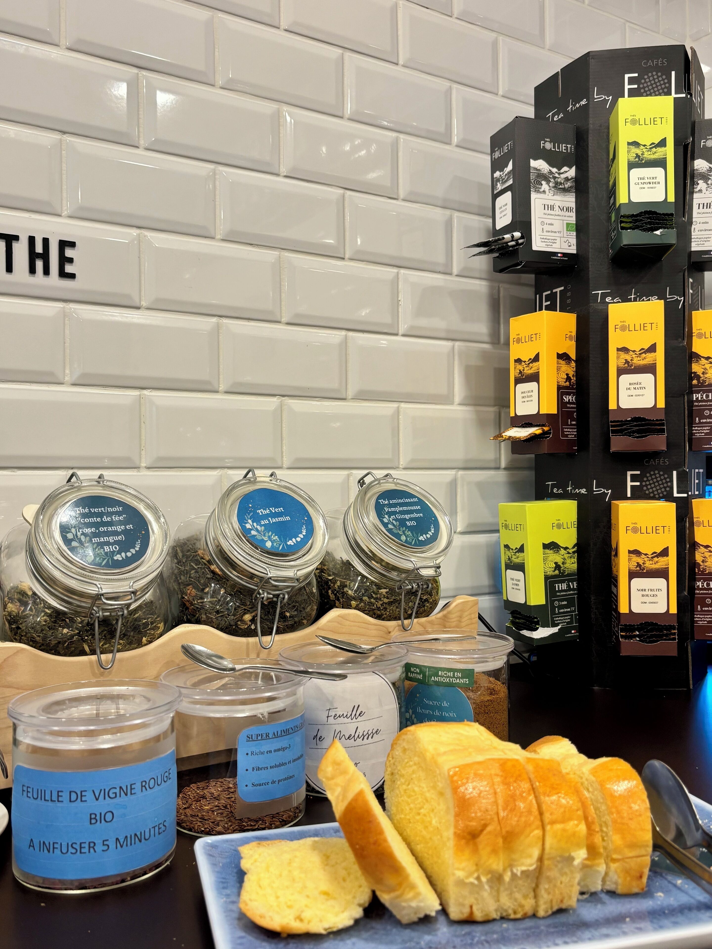 A display of tea boxes, jars of tea, and a loaf of bread on a table.