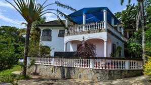 A two-story house with a balcony, stone walls, and a blue awning. - Greenwood Resort (Mtwapa)