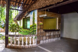 A reception area with a mural, a reception desk, and a thatched roof. - Greenwood Resort (Mtwapa)