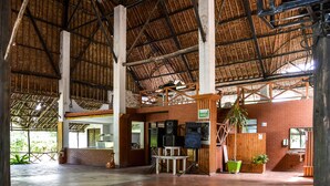 A spacious indoor area with a high ceiling, brick walls, and a thatched roof. - Greenwood Resort (Mtwapa)