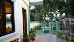 Un patio con un banco, plantas en macetas y una verja.