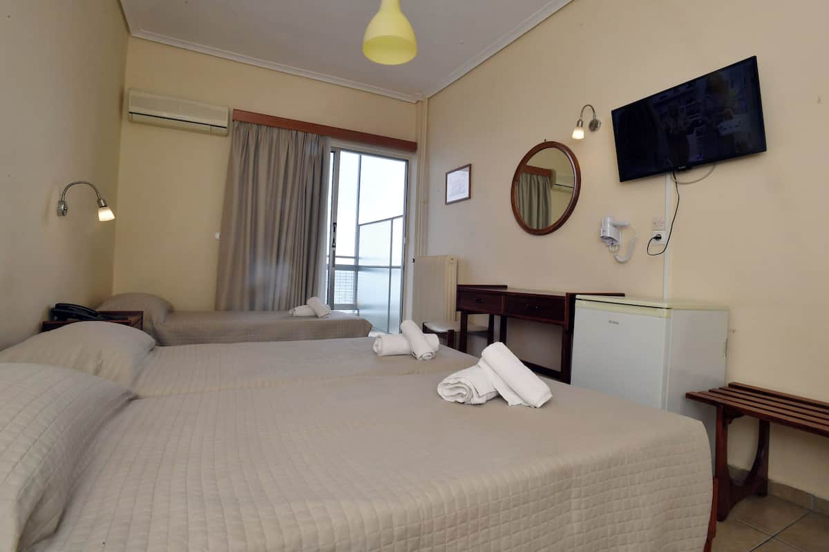 Habitación de hotel con dos camas, un escritorio, televisión, espejo y ventana con cortinas.
