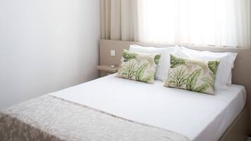 Quarto com cama, luminária pendente e janela com cortinas.