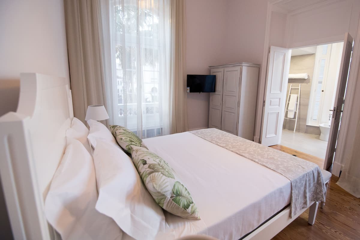Een slaapkamer met een bed, een televisie aan de muur, een kledingkast en een open deur naar een badkamer.