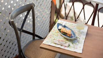 Una mesa de comedor con un plato de comida y un vaso de bebida, una silla y un mantel estampado.