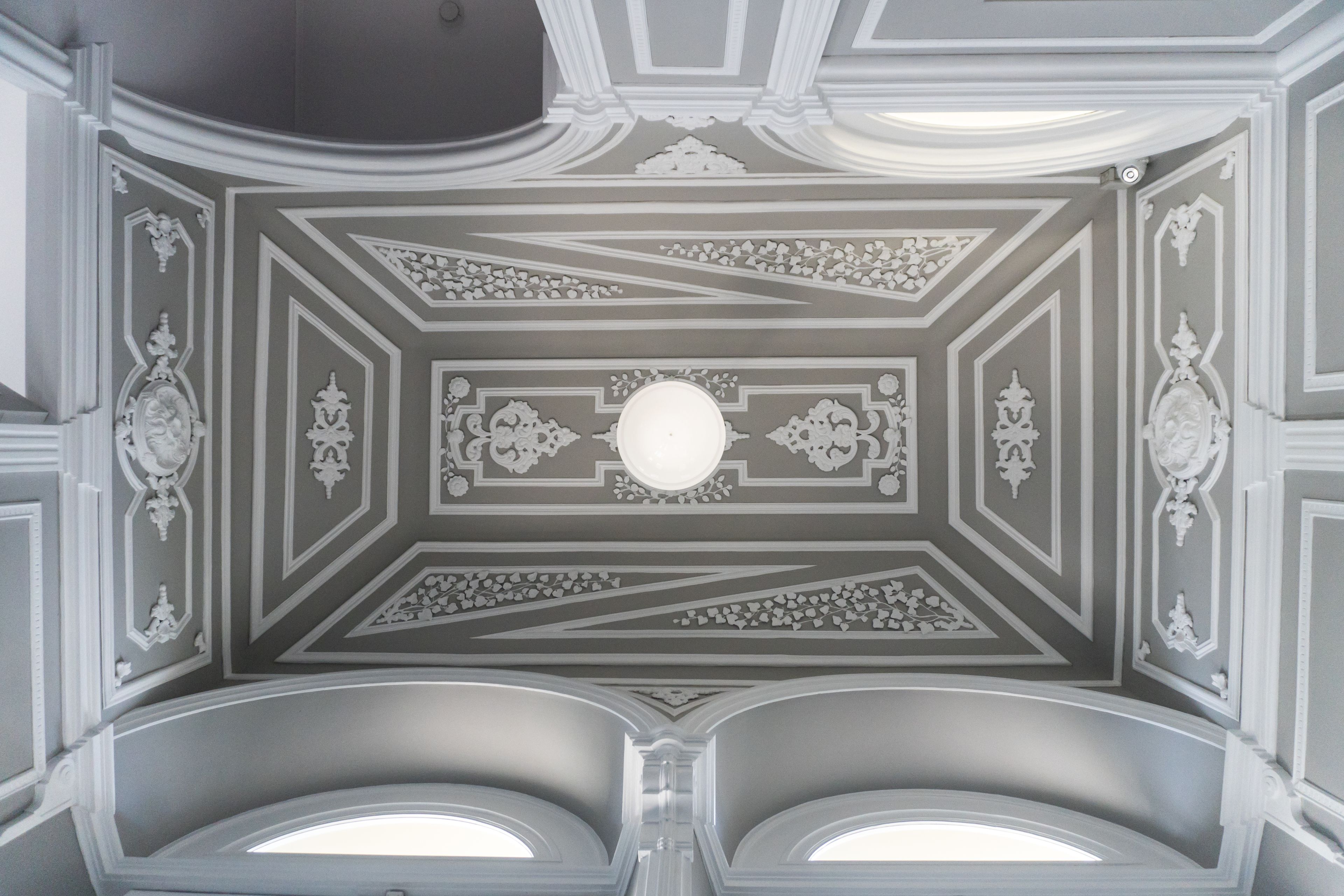 A ceiling with intricate geometric patterns and a central light fixture.