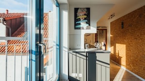 A modern kitchen with a central island, a large window, and a wooden wall. - Aparthotel Pumpengasse (Wolfsburg)