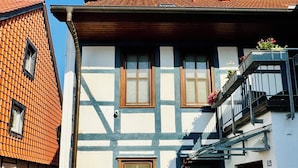 A traditional half-timbered building with a tiled roof, a balcony with railings, and a door with a sign. - Aparthotel Pumpengasse (Wolfsburg)